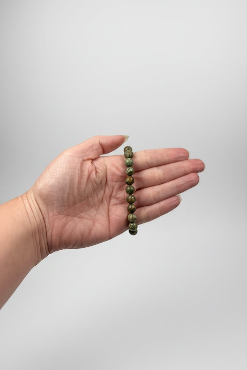 Treasured Energies natural rhyolite beaded elastic bracelet held in a palm against a neutral background