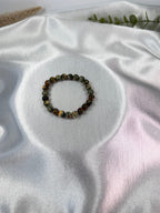 Treasured Energies natural rhyolite beaded elastic bracelet on a white satin background