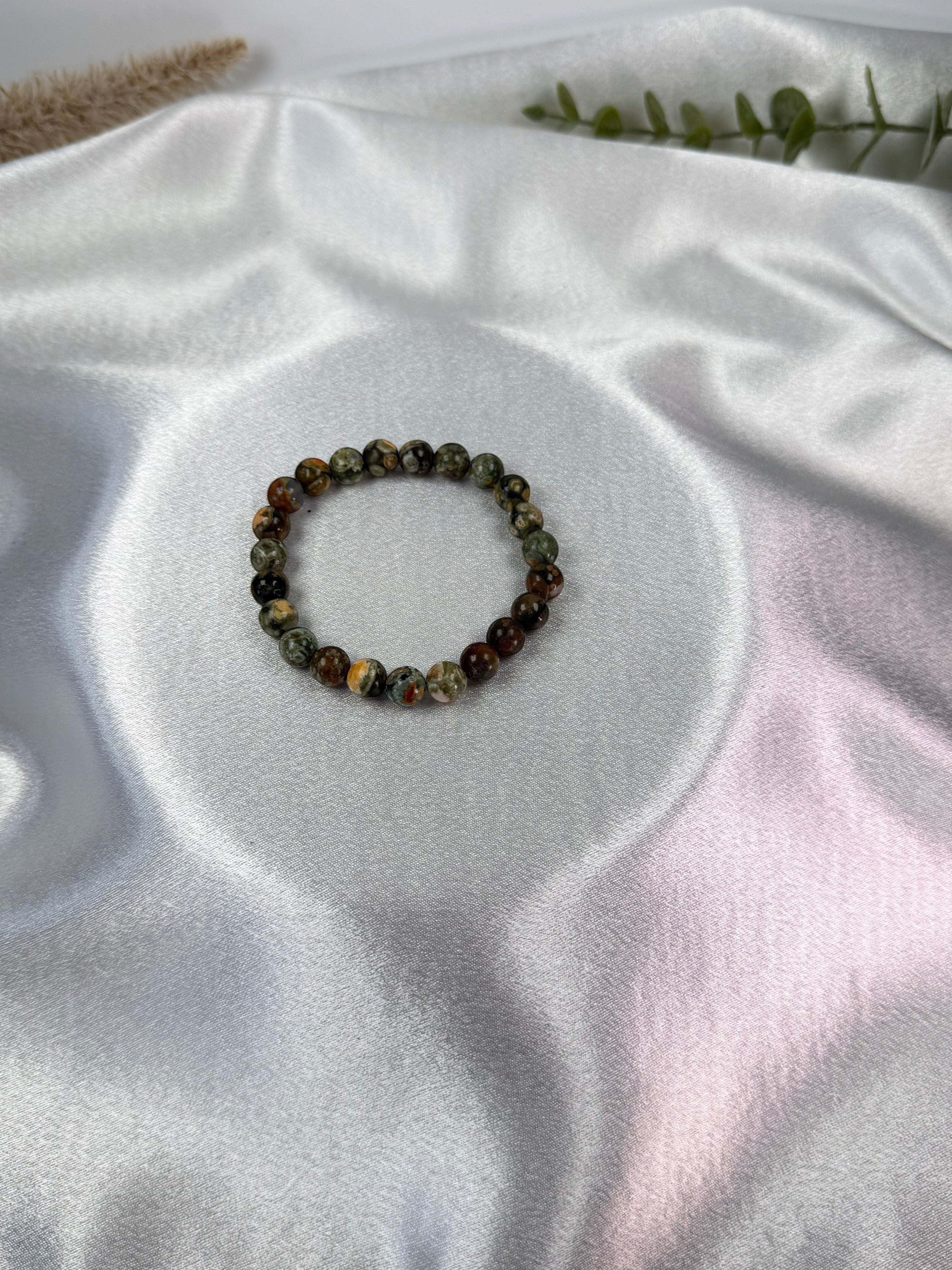 Treasured Energies natural rhyolite beaded elastic bracelet on a white satin background
