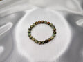 Treasured Energies natural rhyolite beaded elastic bracelet with earthy green and brown tones on a silk background