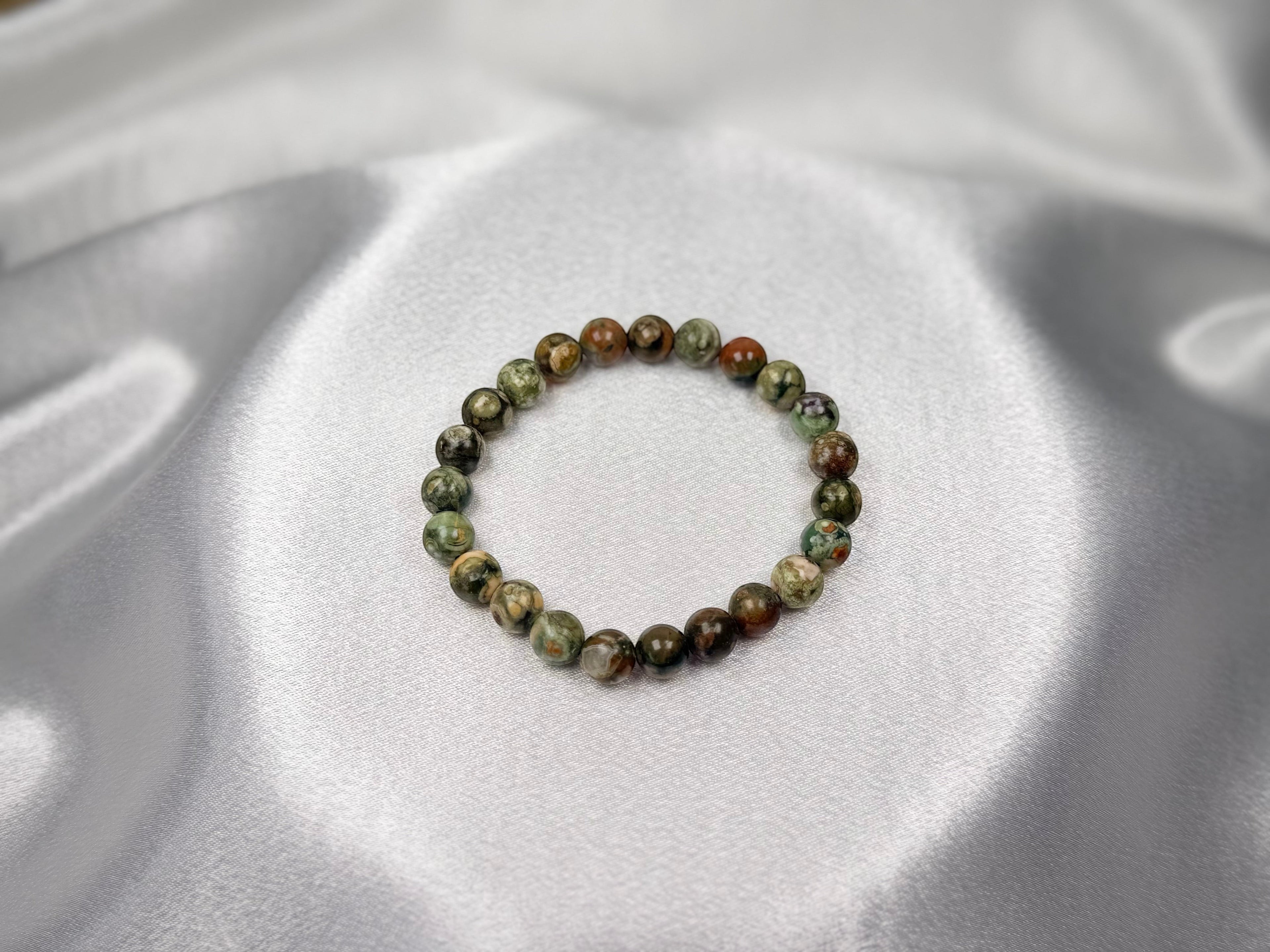 Treasured Energies natural rhyolite beaded elastic bracelet with earthy green and brown tones on a silk background