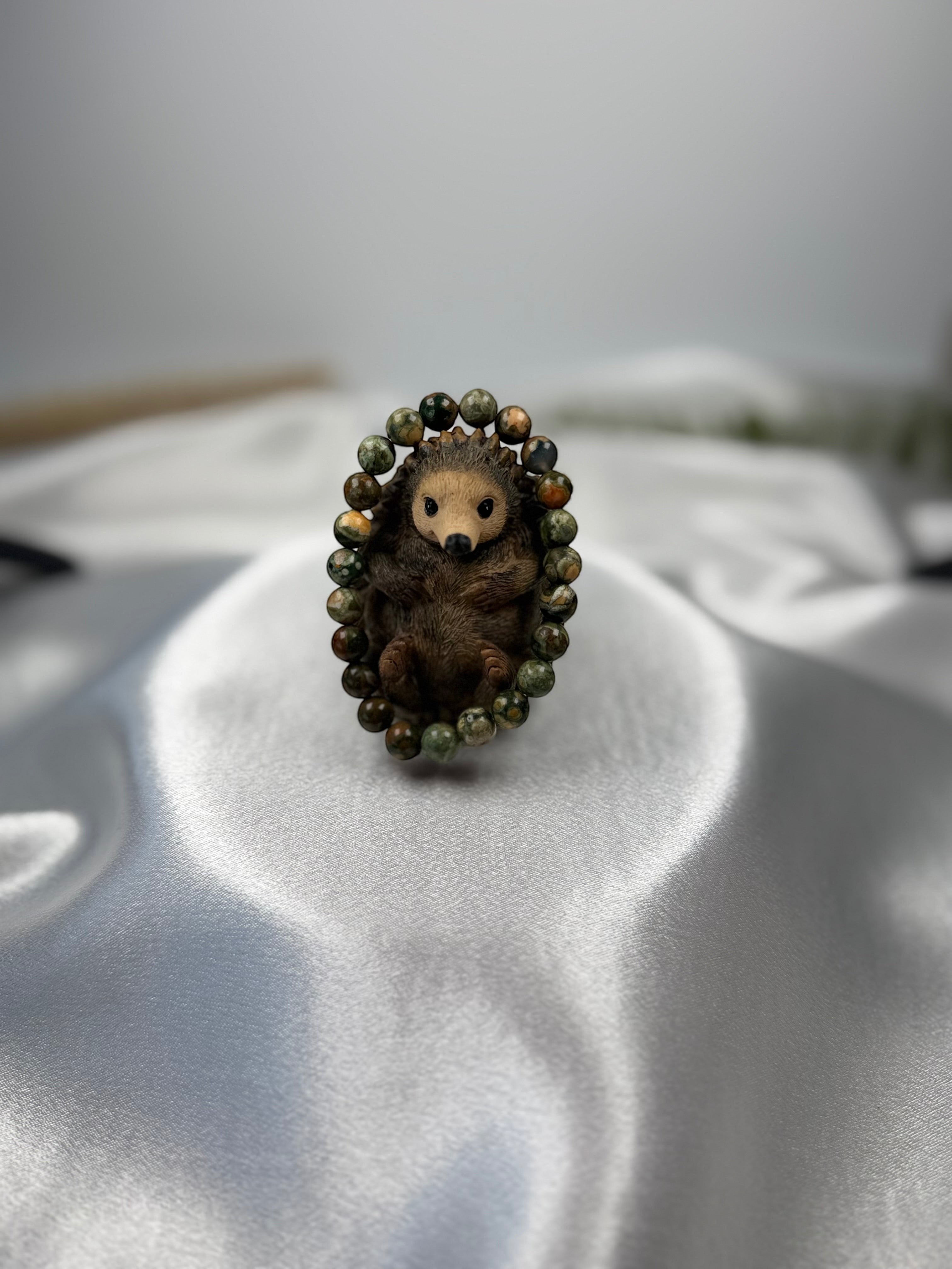 Treasured Energies rhyolite beaded elastic bracelet featuring a cute sculpted hedgehog centerpiece on satin fabric.