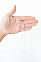 Treasured Energies rose quartz crystal pendant necklace with a silver heart-shaped bail held in a palm