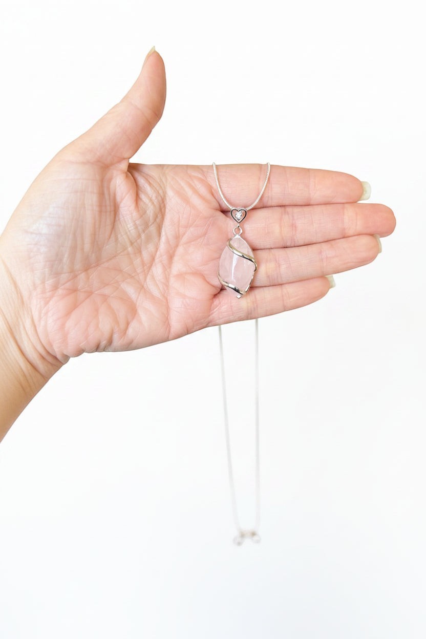 Treasured Energies rose quartz crystal pendant necklace with a silver heart-shaped bail held in a palm