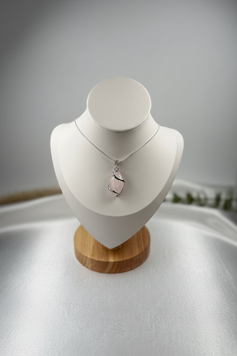 Treasured Energies rose quartz crystal pendant wrapped in silver wire on a delicate chain displayed on a white bust.
