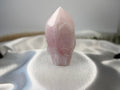 Treasured Energies large rose quartz crystal tower with a polished point and raw base on a white satin fabric