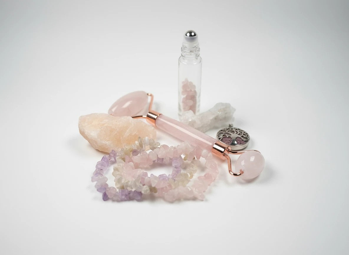 Treasured Energies rose quartz face roller set with crystal bracelets, essential oil vial, and tree of life charm.