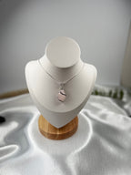 Treasured Energies rose quartz crystal pendant necklace with silver wire wrapping on a white display bust.