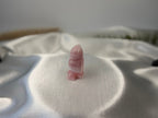 Treasured Energies rose quartz crystal owl carving with a smooth polished finish on a white satin background
