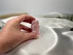 Treasured Energies hand-carved rose quartz owl figurine held against a soft white satin background.