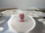 Treasured Energies rose quartz owl carving with a smooth, polished finish resting on a soft white satin fabric.