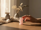 Treasured Energies hand carved rose quartz owl figurine resting on a wooden table with a hand reaching towards it.