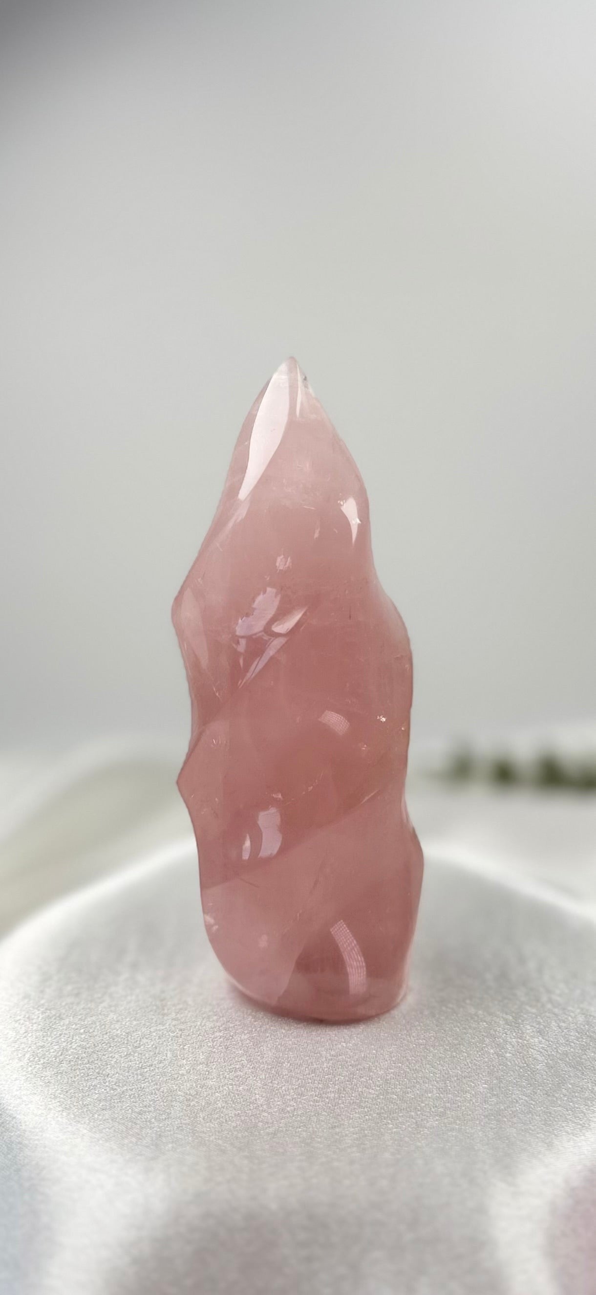 Treasured Energies large rose quartz crystal carved into a polished, translucent pink spiral flame shape.