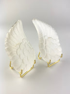 Treasured Energies pair of carved white selenite angel wings displayed on gold metal stands against a white background.