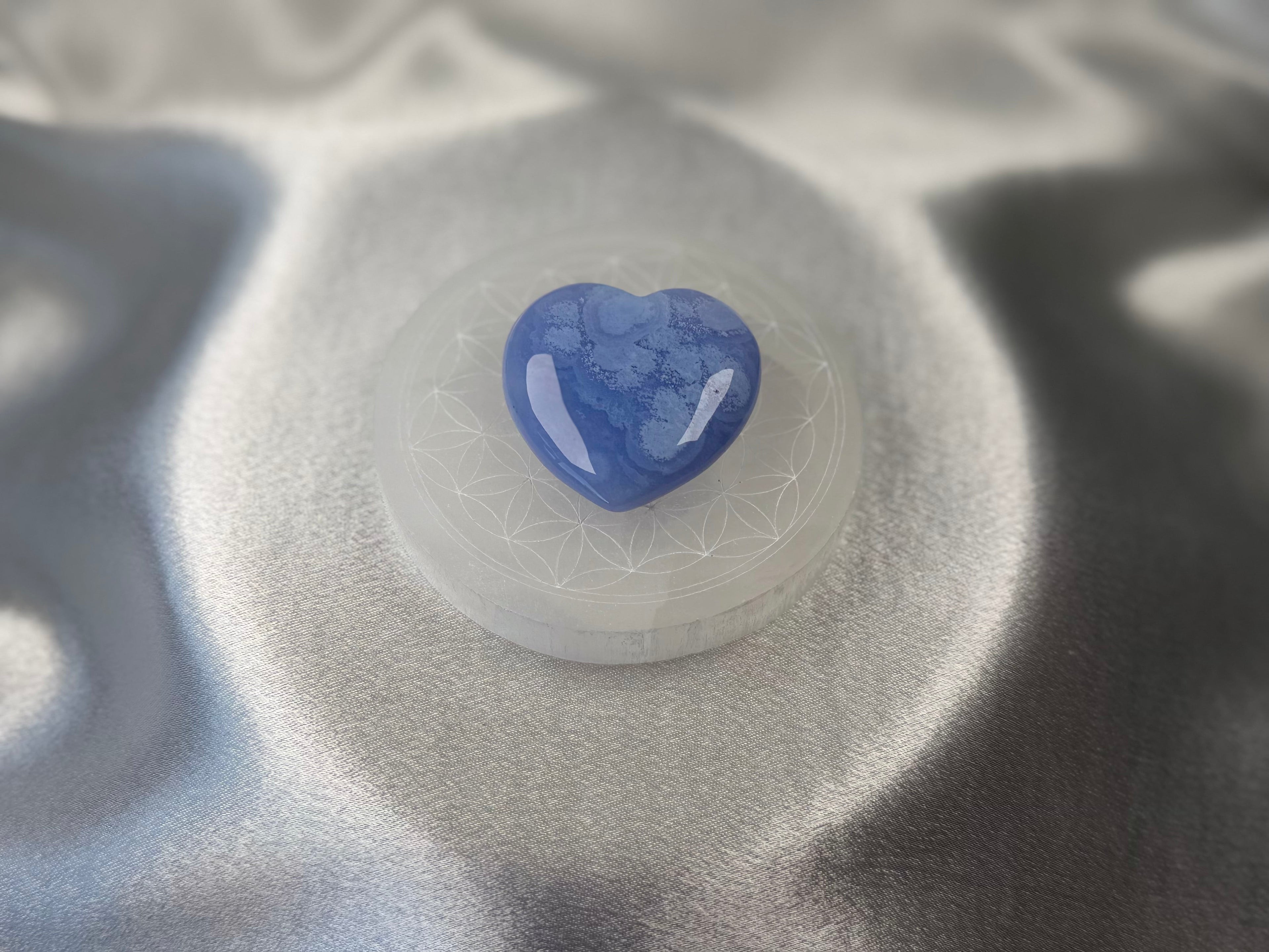 Treasured Energies 8cm round selenite charging plate with sacred geometry engraving and a blue heart crystal on top