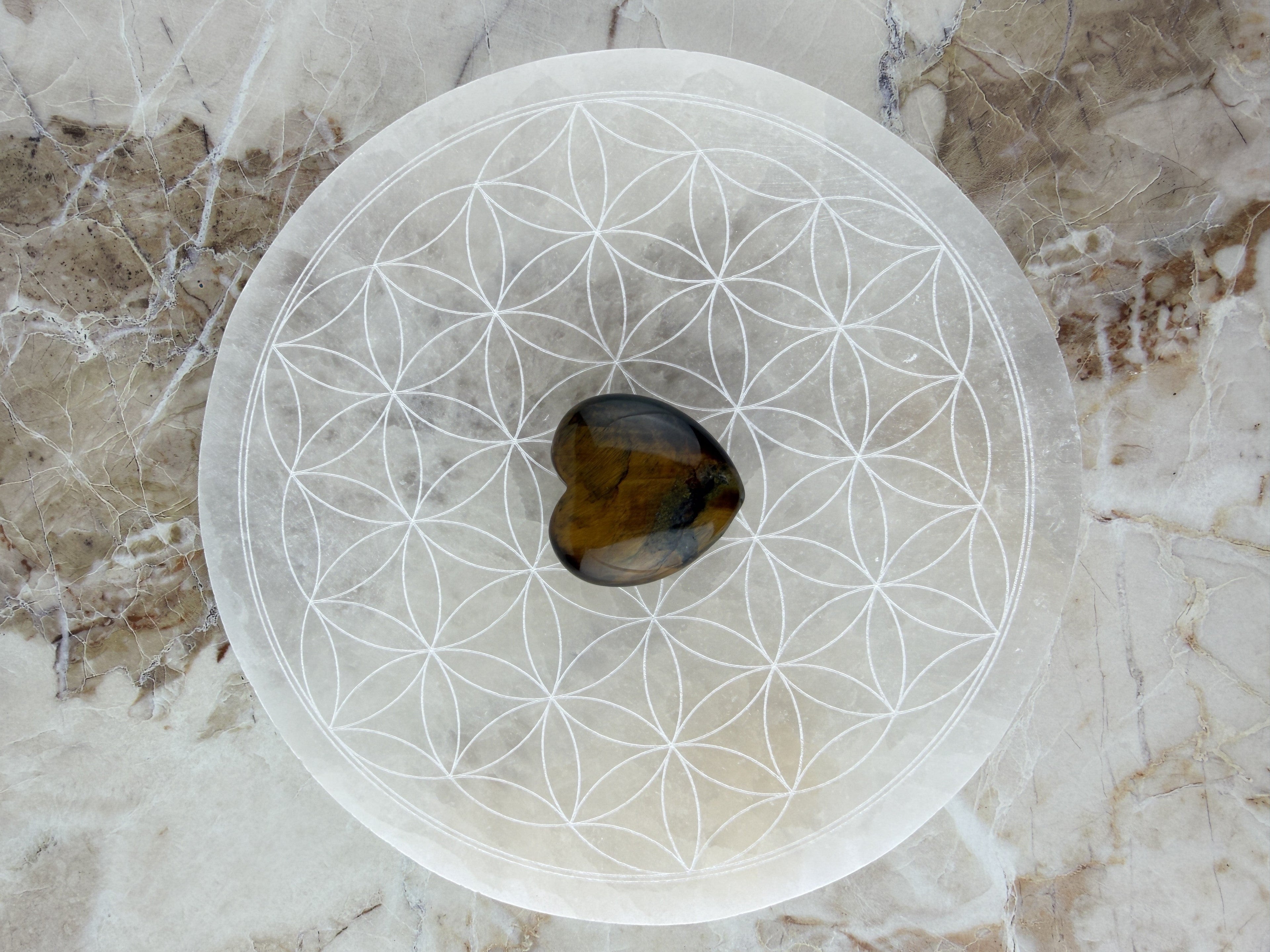 Treasured Energies 14cm round white selenite charging plate with engraved flower of life pattern and heart crystal