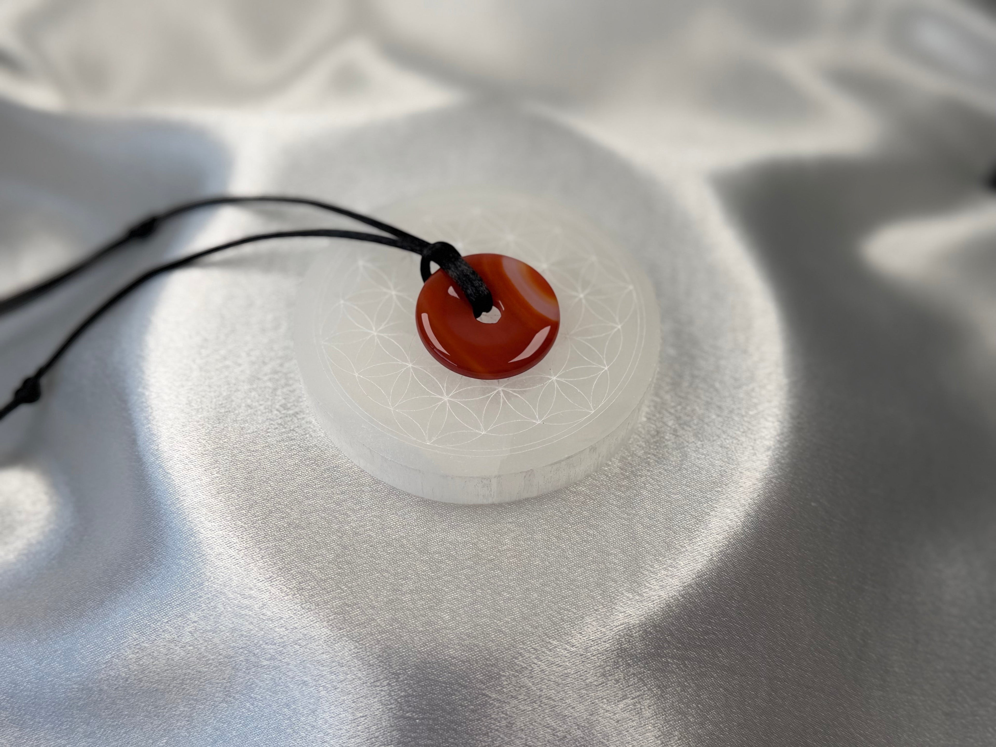Treasured Energies 8cm round white selenite charging plate with sacred geometry engraving and a red carnelian pendant