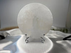 Treasured Energies 14cm round white selenite charging plate with an intricate tree of life engraving on a display stand