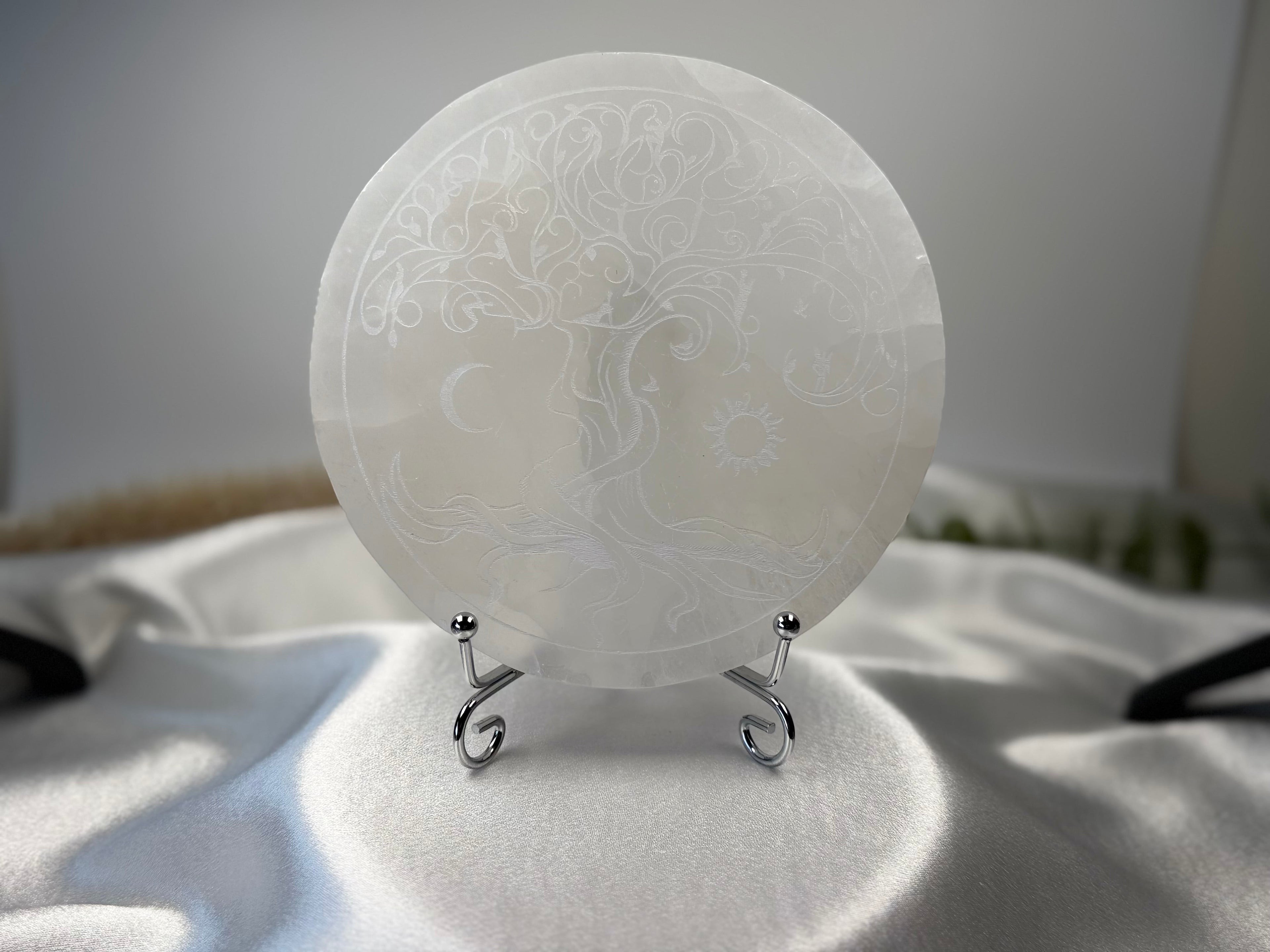 Treasured Energies 14cm round white selenite charging plate with an intricate tree of life engraving on a display stand