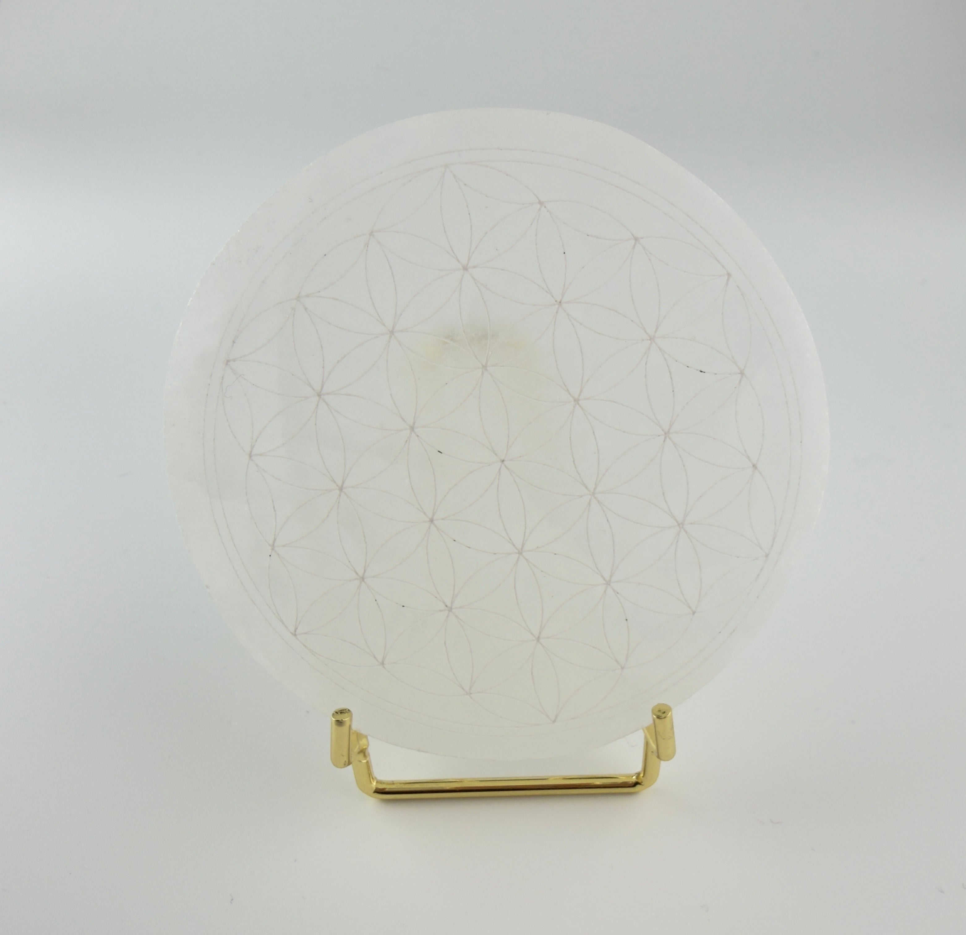 Treasured Energies 8cm round white selenite charging plate with a sacred geometry flower of life engraving on a stand