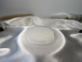 Treasured Energies 8cm round white selenite charging plate with sacred geometry engraving on a silky white fabric.