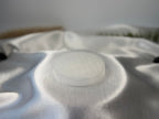 Treasured Energies 8cm round white selenite charging plate with sacred geometry engraving on a silky white fabric.