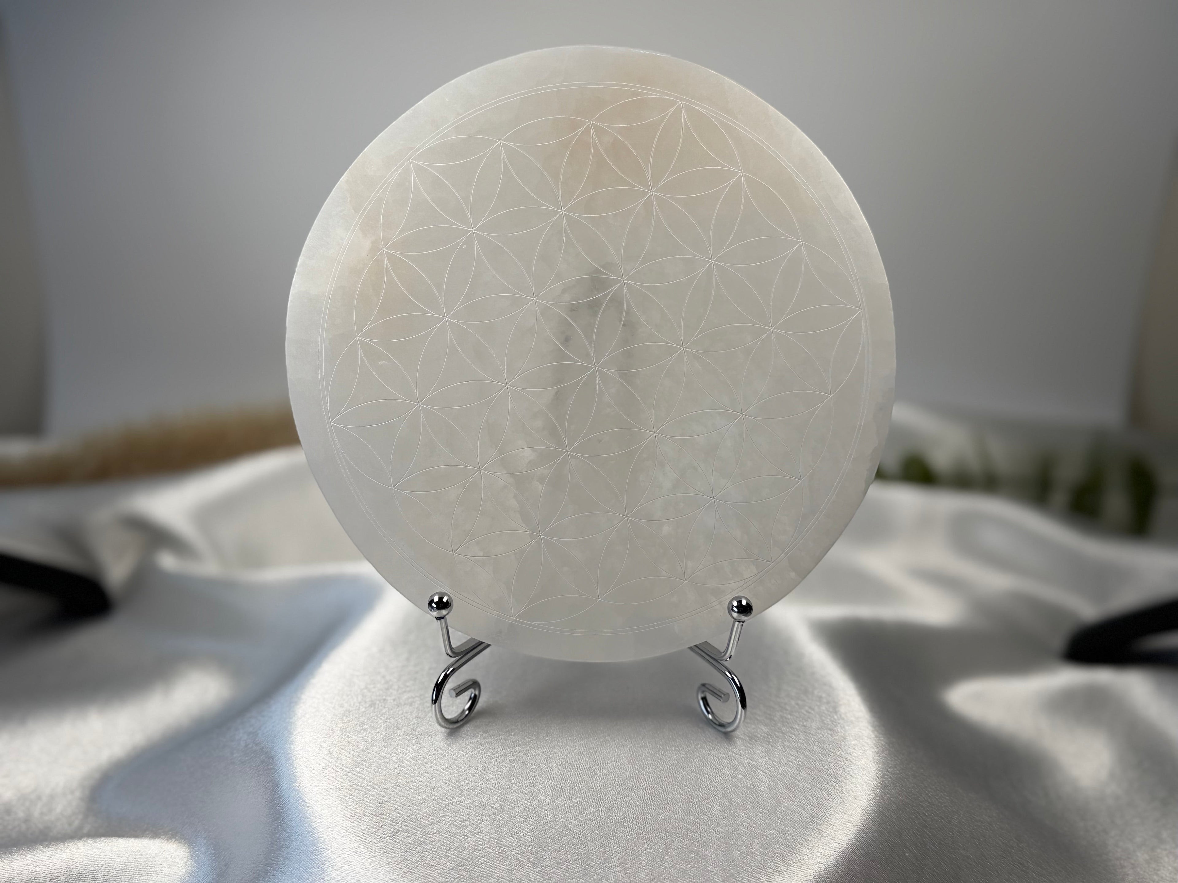Treasured Energies 14cm round white selenite charging plate with a delicate engraved flower of life sacred geometry design.