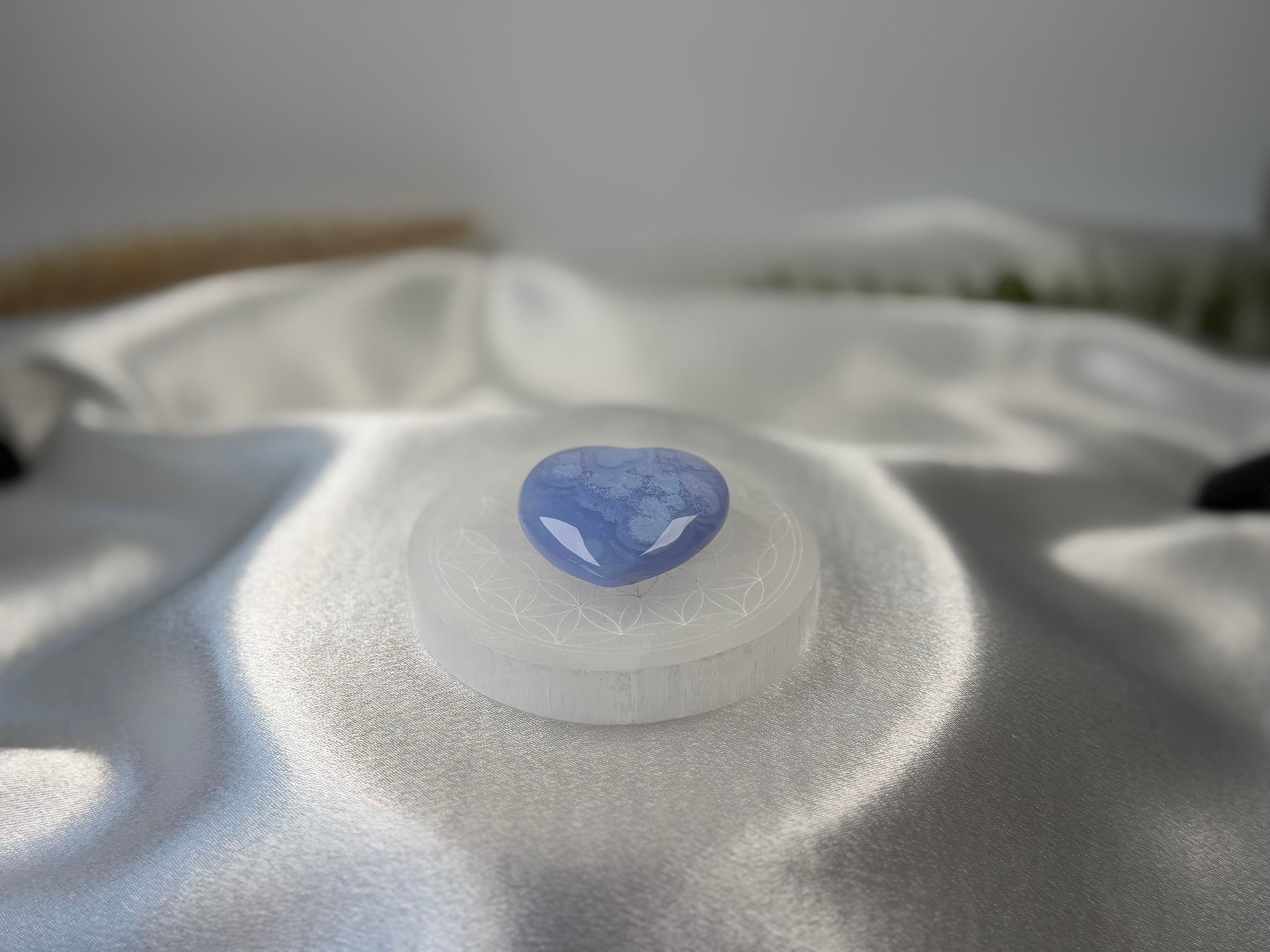 Treasured Energies 8cm round selenite charging plate with sacred geometry engraving holding a blue heart crystal