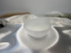 Treasured Energies hand carved white selenite crystal bowl resting on a soft, shimmering white satin fabric.