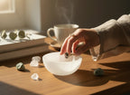 Treasured Energies hand carved white selenite crystal bowl on a wooden table with rings and small stones