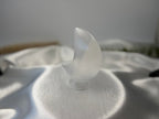 Treasured Energies hand-carved white selenite crescent moon crystal sculpture resting on a soft white satin fabric.