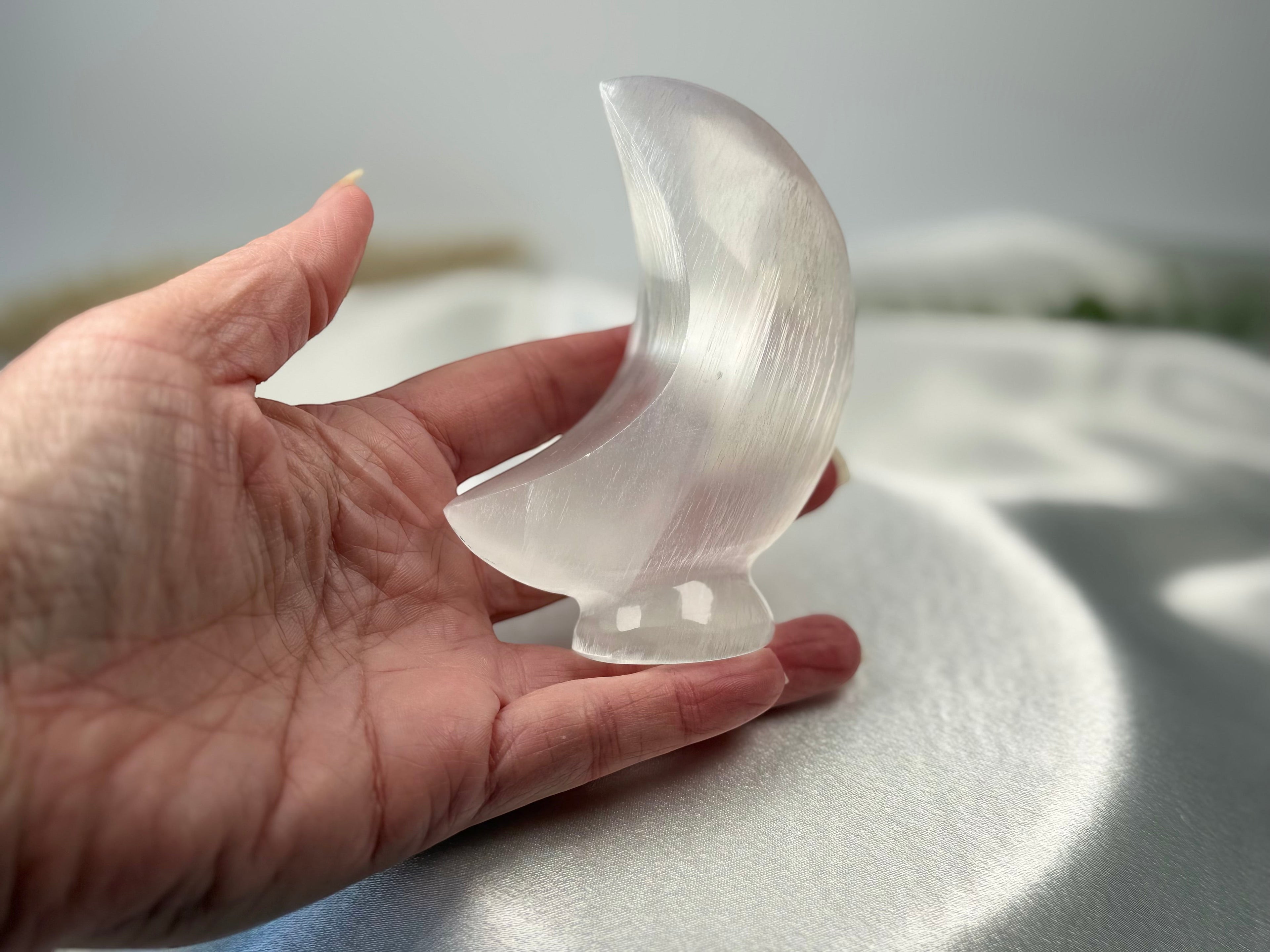 Treasured Energies hand carved translucent white selenite crescent moon crystal sculpture held in a palm
