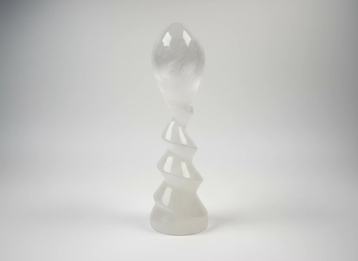 Treasured Energies translucent white selenite crystal sculpture with a spiral design on a plain background