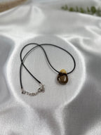 Treasured Energies Septarian crystal pendant necklace on a black cord, featuring brown and yellow mineral patterns.