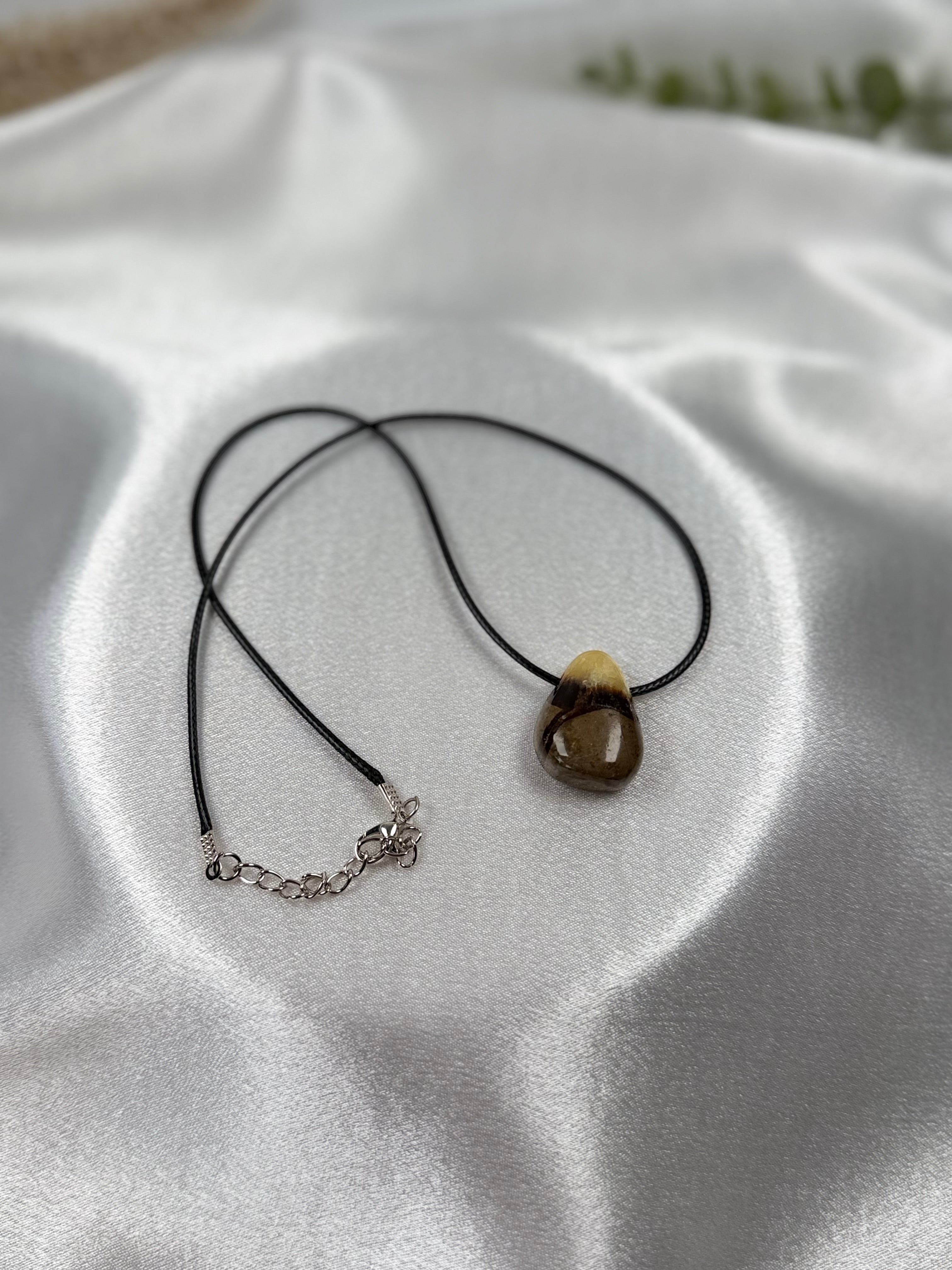 Treasured Energies Septarian crystal pendant necklace on a black cord, featuring brown and yellow mineral patterns.