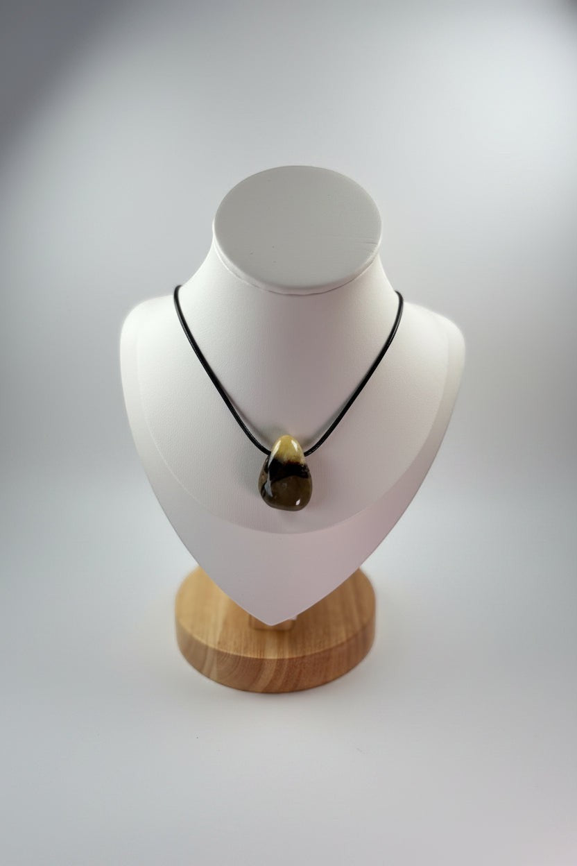 Treasured Energies Septarian crystal pendant on a black cord necklace displayed on a white mannequin bust.