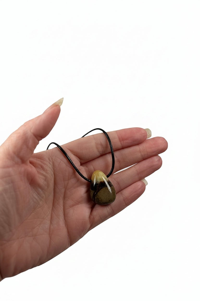 Treasured Energies Septarian crystal pendant necklace with brown and yellow mineral patterns held in a palm