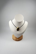 Treasured Energies polished Septarian stone pendant necklace on a black cord displayed on a white mannequin bust.