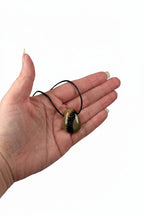 Treasured Energies polished Septarian stone pendant necklace held in a palm, showing brown and yellow mineral patterns.