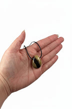 Treasured Energies polished Septarian stone pendant necklace with brown and yellow mineral patterns held in a palm.