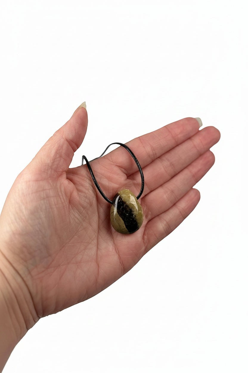 Treasured Energies polished Septarian pendant necklace with brown and yellow mineral patterns held in a palm.