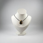 Treasured Energies polished Septarian stone pendant necklace featuring brown and yellow geometric patterns on a black cord.