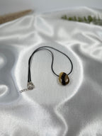 Treasured Energies polished Septarian stone pendant necklace with brown, yellow, and grey mineral patterns on a black cord.