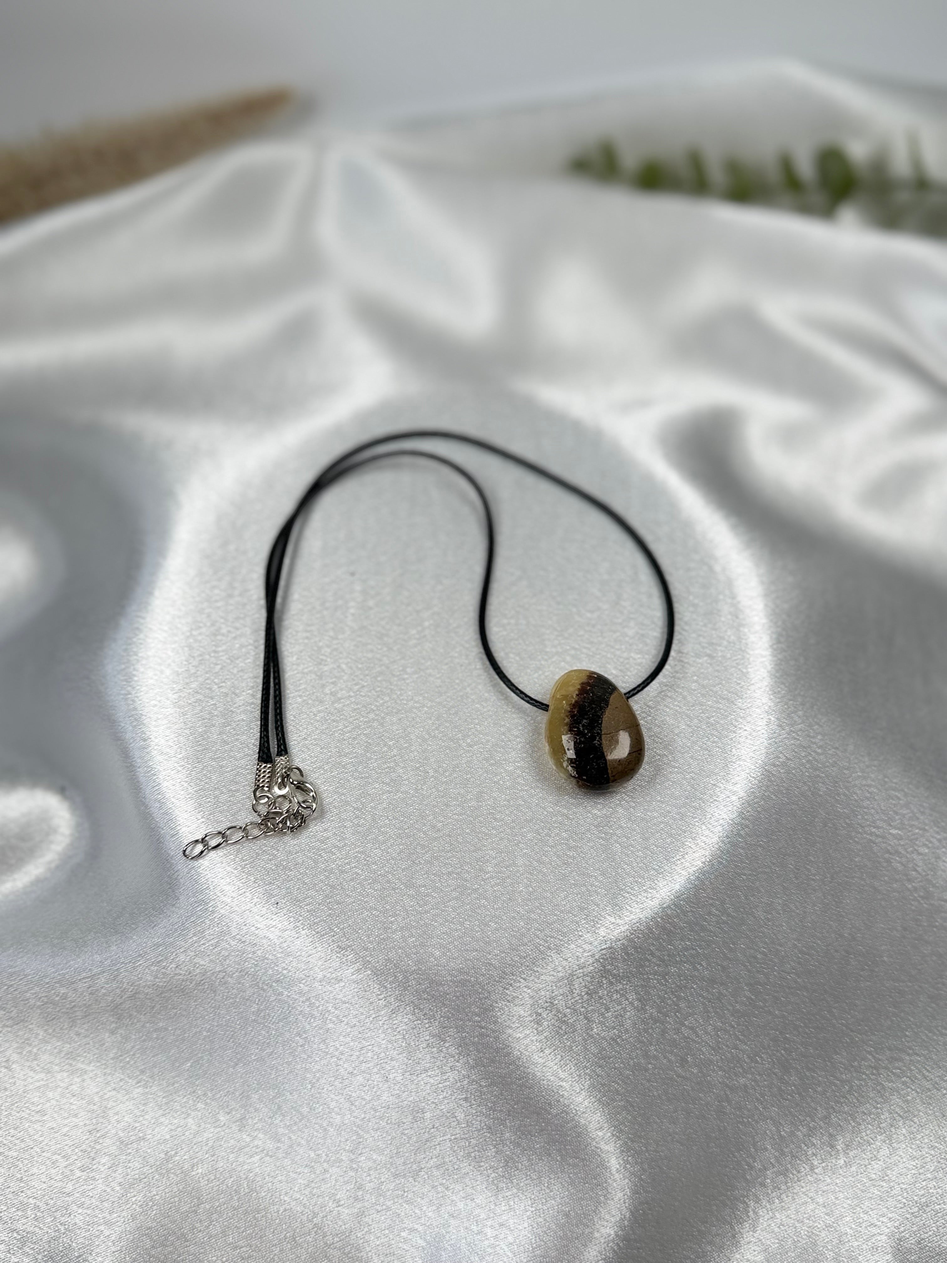 Treasured Energies polished Septarian pendant necklace with brown, yellow, and grey mineral patterns on a black cord.