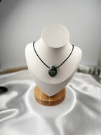 Treasured Energies seraphinite crystal pendant on a black cord necklace displayed on a white mannequin bust.