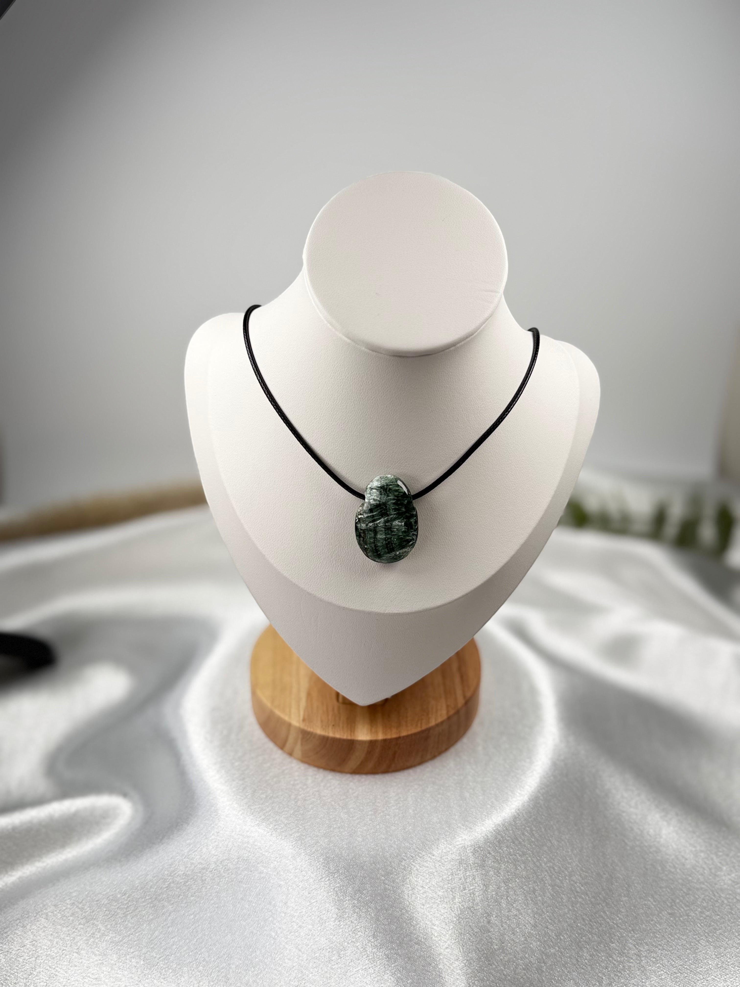 Treasured Energies seraphinite crystal pendant on a black cord necklace displayed on a white mannequin bust.