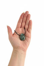 Treasured Energies seraphinite crystal pendant on a black cord held in a palm for scale