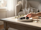 Treasured Energies polished black shungite heart stone held by a hand on a white tray in a sunlit room