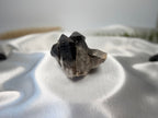 Treasured Energies raw smoky quartz crystal cluster with deep brown and grey tones on a white satin background.