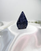Treasured Energies polished royal blue Sodalite crystal flame sculpture with white mineral veining on a white cloth.